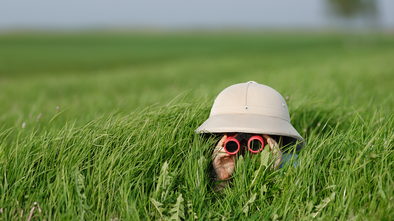 Little Boy with Binoculars and safari Hat, laying in the grass s Informa Sea